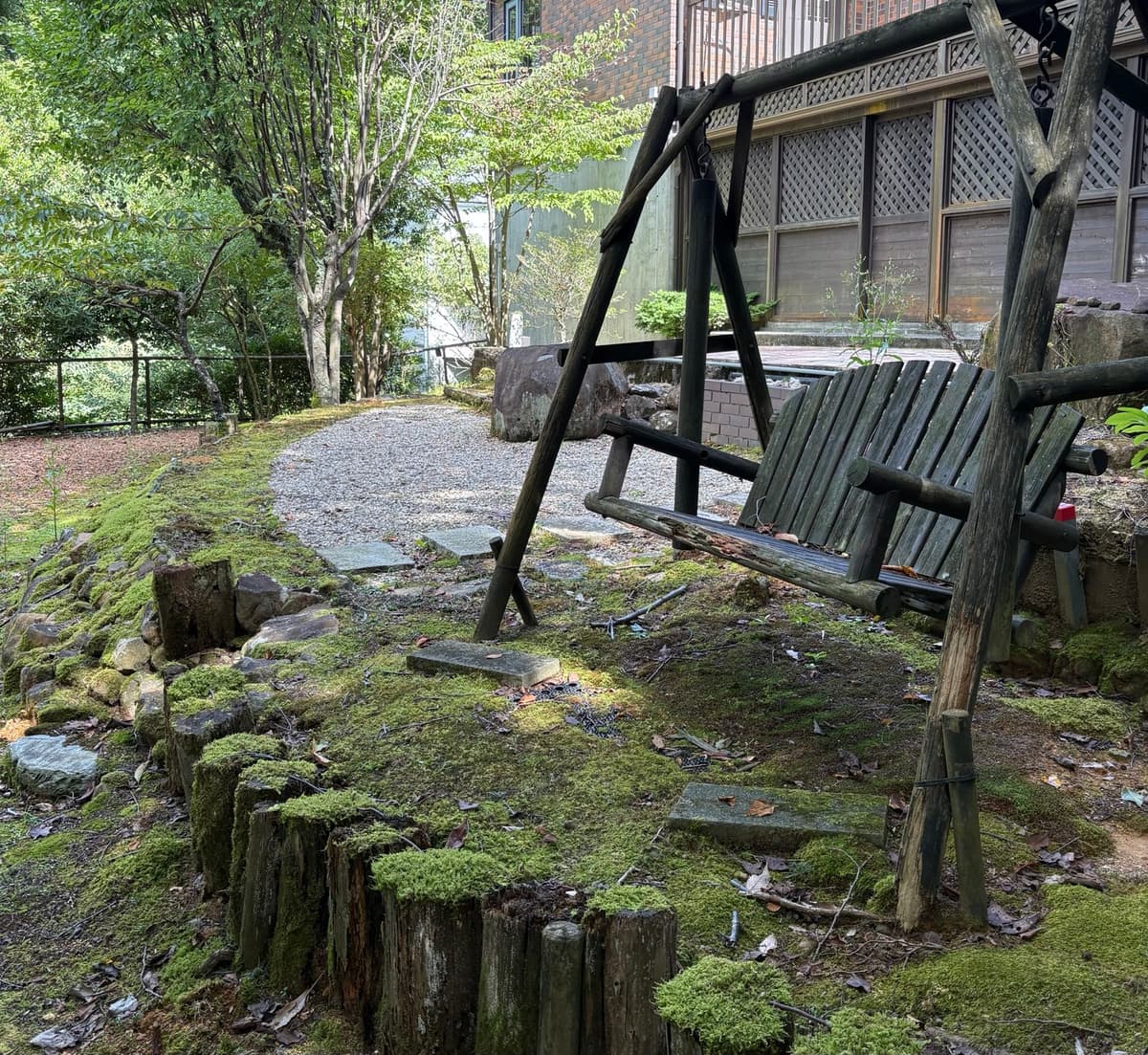 伊東の別荘の庭。木々と苔に囲まれた木製のブランコ